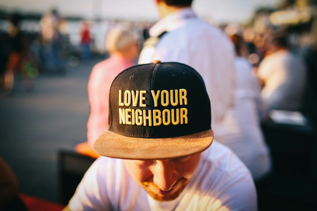 A young man wearing a cap that reads 'Love Your Neighbor'