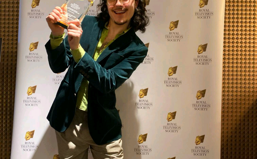 Ryan Johnson holding an RTS screenwriting award